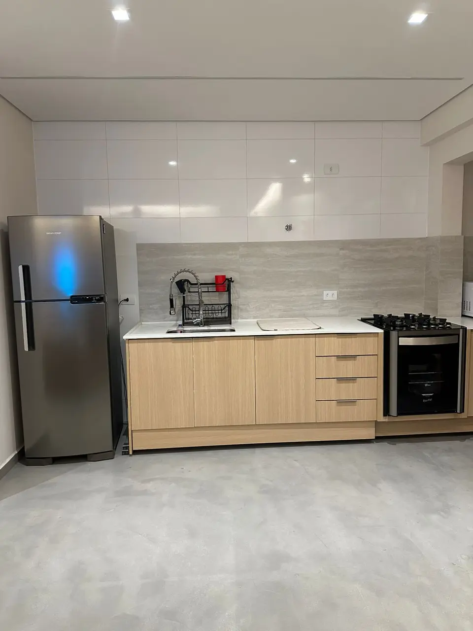 Cozinha com bancada branca e armários em madeira clara