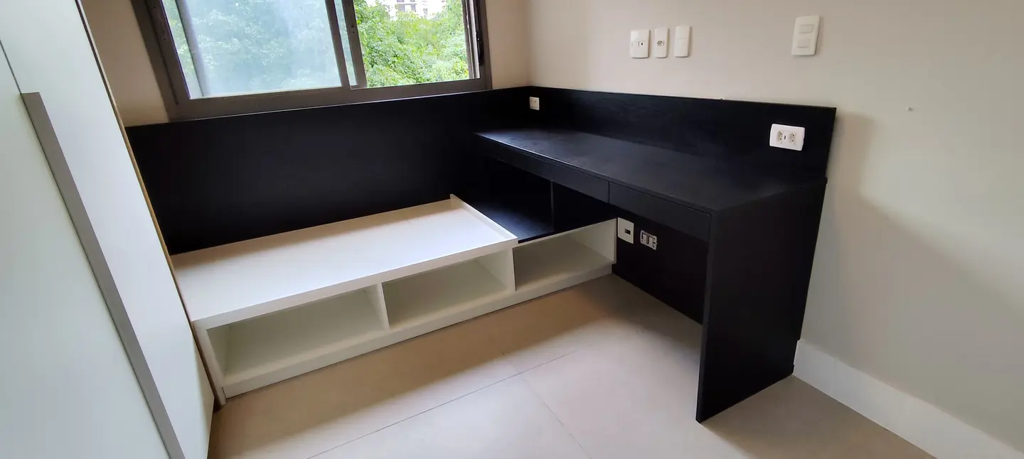 Bancada preta com nichos e cama em dormitório home office